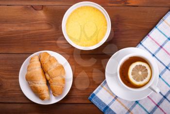 Tea with lemon and honey croissants on a kitchen table.