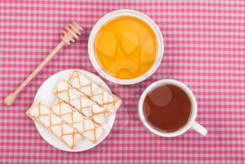 Tea biscuits and honey on the tablecloth.