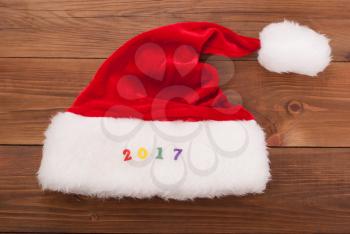Hat of Santa Claus and the numbers 2017 on the wooden background.