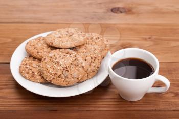Cup of coffee and cookies on the wooden table.