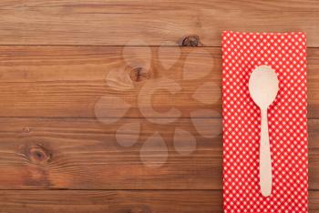 Spoon and napkin on wooden background.