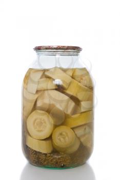 Canned zucchini in a glass jar on a white background.