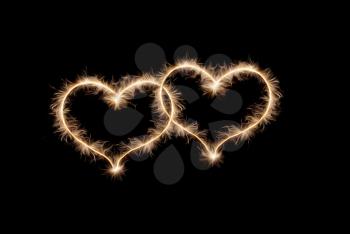 Two hearts drawn by sparklers on a black background.