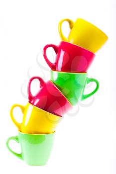 Beautiful yellow, red, green color cups. Leaning tower stack of clean different cups isolated on white background