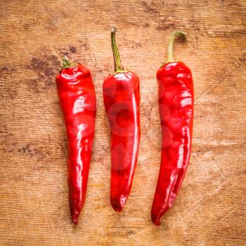 Red hot chili peppers on old wooden table surface texture background