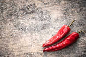Red hot chili peppers on old wooden table surface texture background