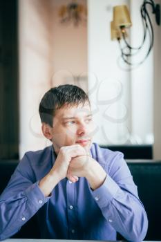Caucasian Handsome Thinking Man In Blue Shirt Sitting In Cafe