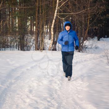 Portrait Of Young Man Athlete Is Jogging In Snowy Landscape