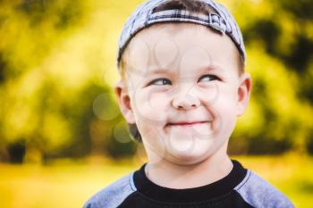 Happy Caucasian Child Boy Smiling Outdoors With Stripped Cap, Green Nature Background
