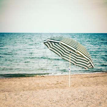 Striped Umbrella On Sandy Beach. Toned Instant Photo