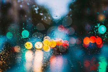 Drops Of Rain Water In Night Or Evening Street Lights On Blue Glass Background. Street  Bokeh Boke Lights Out Of Focus. Autumn Abstract Backdrop