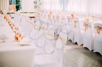 Decorative White Mantles And Colored Ribbons On Chairs At Festive Table. Chairs And Table Covered With Cloth.