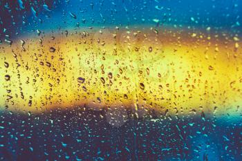 Drops Of Rain On Glass On Glass Background. Instant toned photo. Colorful background