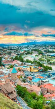 The Top View Of Old Colorful Town And Kura Mtkvari River Under Bridges In Summer Tbilisi, Georgia Beautiful Scenic Sunset Sunrise Dawn Cloudy Sky Background.