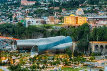 Concert Music Theatre Exhibition Hall In Shape Of Two Metal Glass Tubes Of Hi-Tech Architecture Style Located In Rike Park Of Tbilisi Georgia. Presidential Administration Palace In Evening Back From.
