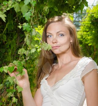 closeup portrait of a beautiful woman among green leaves in the garden