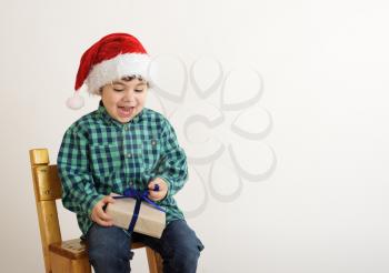 happy boy in a cap of Santa Claus opens Christmas gift