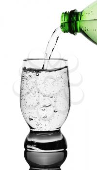 Top view of mineral water being poured into glass from green bottle. isolated clipping paths