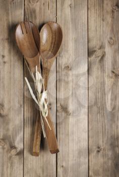 brown wooden spoon with a fork for the salad on the table from the old boards