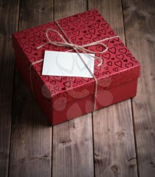 red gift box (package) in hearts with  card on old wooden background.