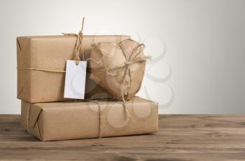 Heart and box wrapped in brown kraft paper on wooden table and grey background
