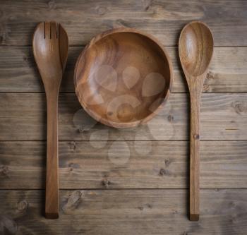 Cutlery made of wood, a spoon, a fork and a bowl on the table