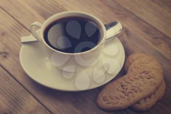 cup of coffee with cookies on old wooden table.