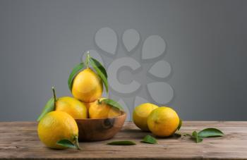 lemons with green leafs in a wooden bowl on the table