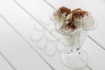 glass of ice cream with chocolate shavings on a white wooden table