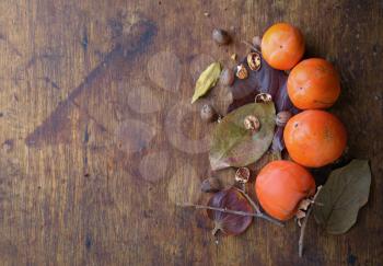 ripe persimmon with pecans on the old wooden background