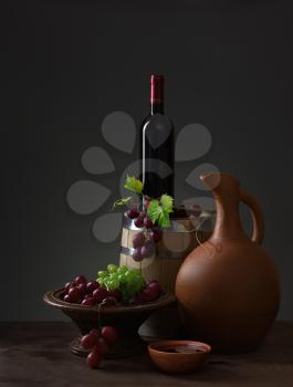 Bottle of red wine, pitcher, grapes and wooden barrel