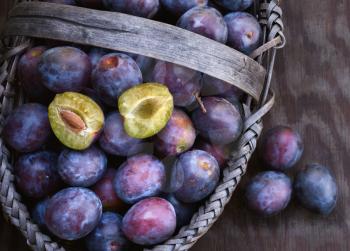 Fresh ripe black plums in a basket closeup