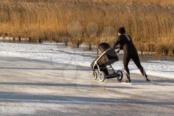 A woman is skating with a childrens buggy on the famous dutch Bonkevaart Friese Elfstedentocht