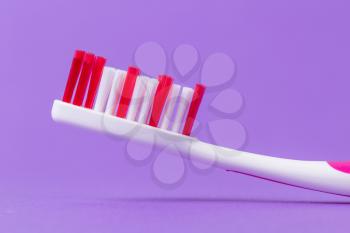 A pink toothbrush on a purple background