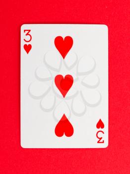 Old playing card (three) isolated on a red background