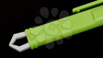 Used green plastic forceps for pets to remove ticks from the animal skin isolated on black studio background