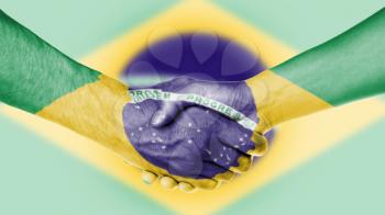 Man and woman shaking hands, arms wrapped in the flag of Brazil
