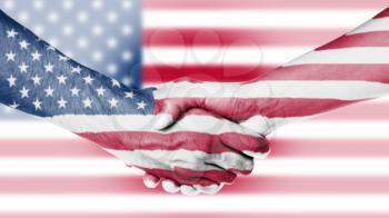 Man and woman shaking hands, arms wrapped in the flag of the USA