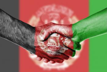 Man and woman shaking hands, wrapped in flag pattern, Afghanistan