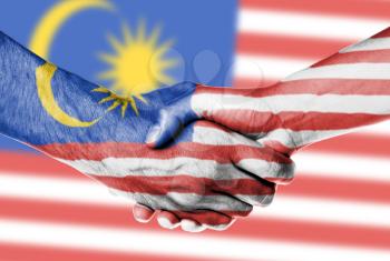 Man and woman shaking hands, wrapped in flag pattern, Malaysia