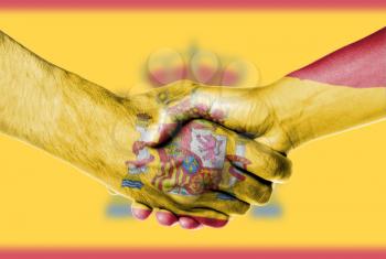 Man and woman shaking hands, wrapped in flag pattern, Spain