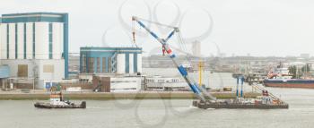 ROTTERDAM, THE NETHERLANDS - JUNE 22: Close-up of a tugboat dragging a crane in the busy port of Rotterdam, Rotterdam, Holland, June 22, 2012