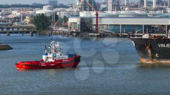 ROTTERDAM, THE NETHERLANDS - JUNE 22: Two tugboats manoeuvring an oil tanker in the dutch harbor of Rotterdam, Rotterdam, June 22, 2012