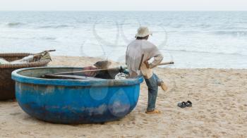 Unidentified man on a beach with Vietnamese fishing boat