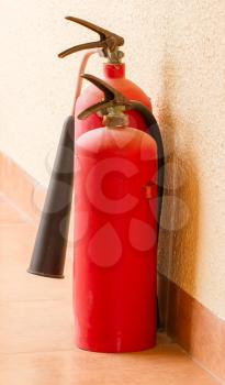 Two red fire extinguishers on a floor