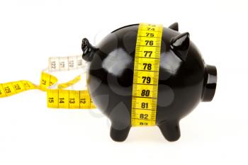 Black piggy bank with measuring tape on white background