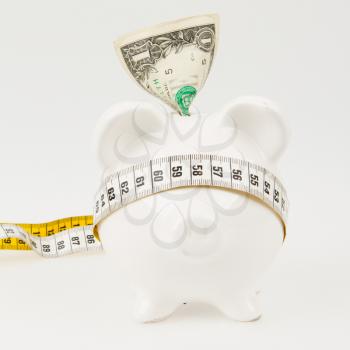 White piggy bank with measuring tape on white background