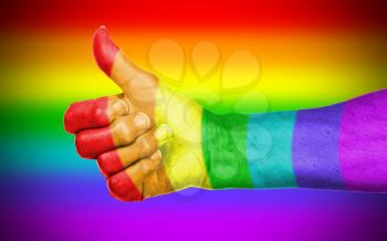 Old woman with arthritis giving the thumbs up sign, rainbow flag pattern