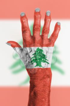 Hand of an old woman wrapped in flag of Lebanon