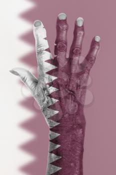 Hand of an old woman wrapped in flag of Qatar